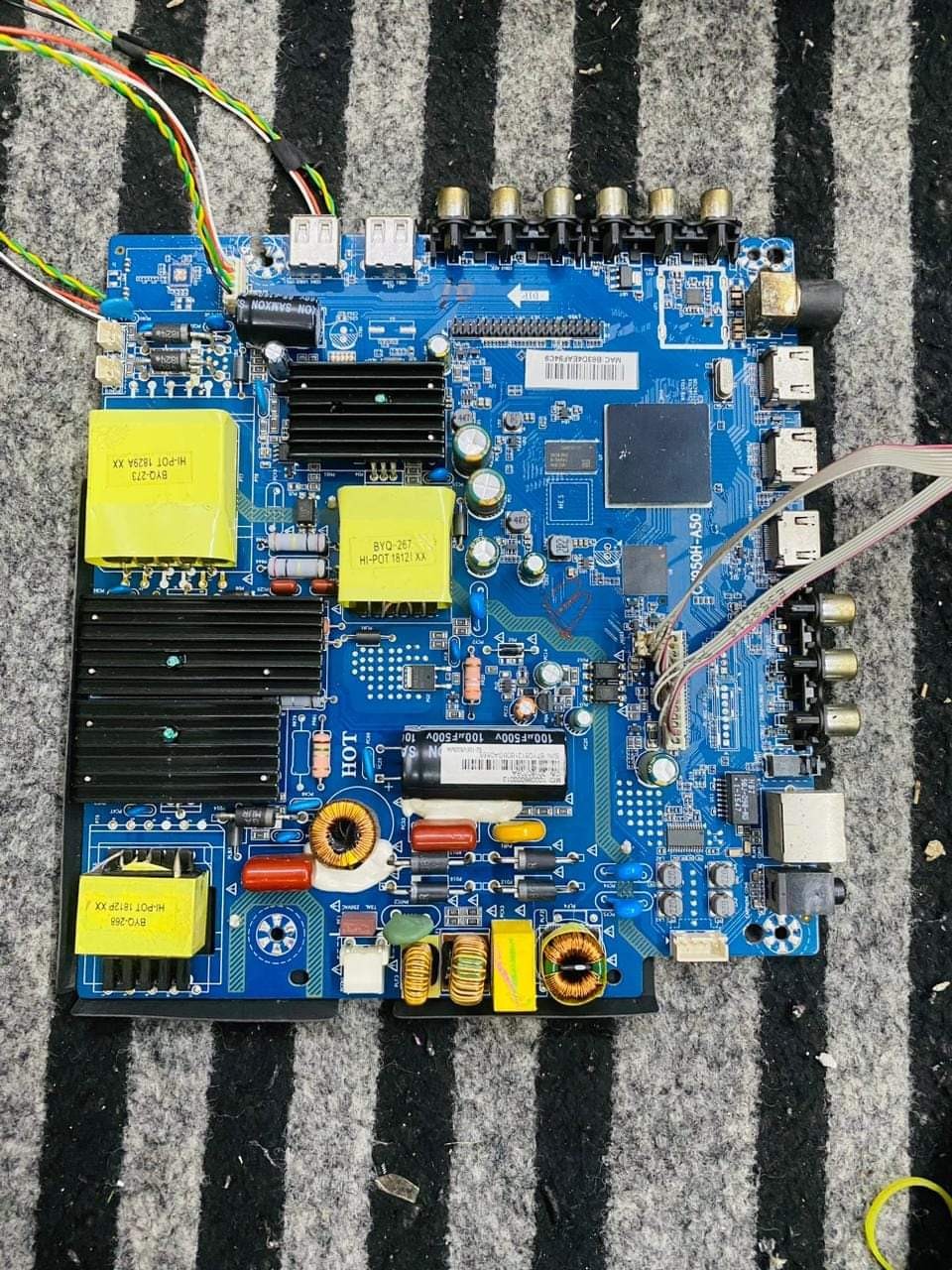 Blue LED TV power supply board (PSU) with yellow transformers and capacitors.